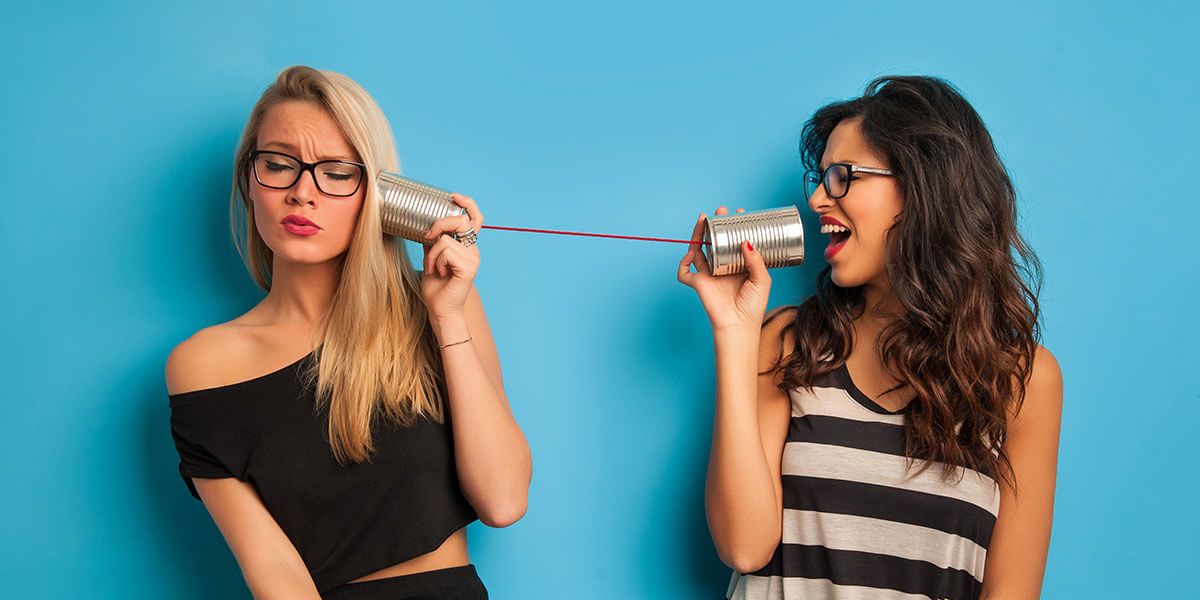 The picture shows two women communicating with two tin cans via a thread. In times of COVID-19 and spacing, online therapy or online coaching is a safe alternative to seek support and communicate.