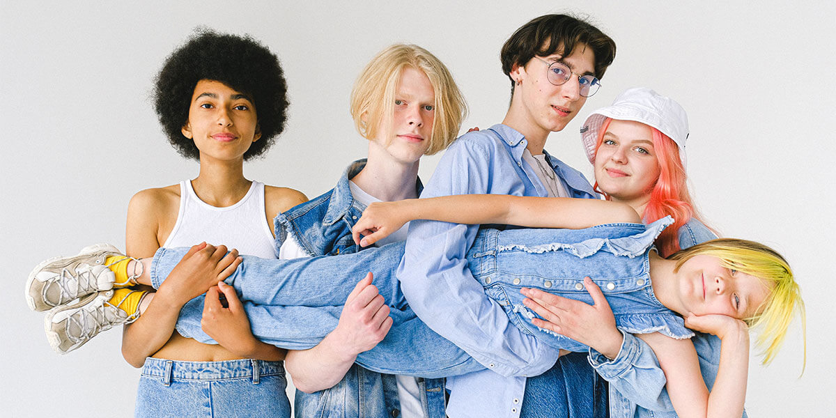 Das Bild zeigt 5 coole Teenager, die eine Mädchen quer halten